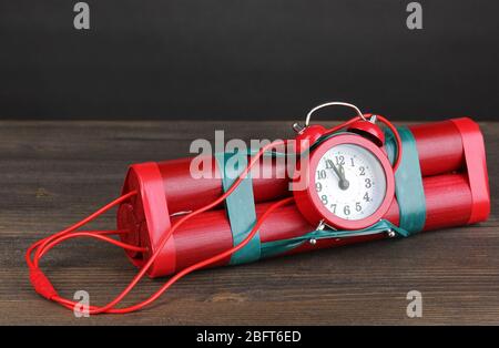 Bombe à retardement à base de dynamite sur table en bois sur fond gris Banque D'Images