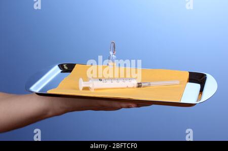 Plateau de maintien des mains avec seringue et médicaments sur fond bleu Banque D'Images