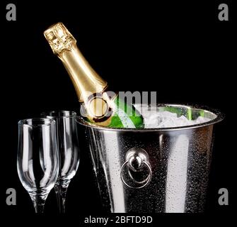 Bouteille de champagne dans un seau isolé sur noir Banque D'Images