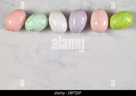 Vue en haut sur les œufs de Pâques mouchetés colorés sur un fond de marbre. Contient un chemin de découpe facultatif autour des œufs de Pâques. Banque D'Images