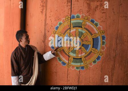 Un guide à côté d'une « roue de la vie » à Jakar Dzong, district de Bumthang, Bhoutan. Banque D'Images