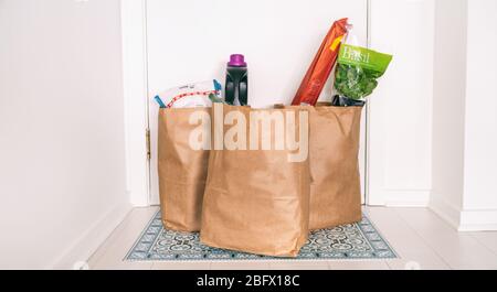 Livraison en ligne d'épicerie réception de sacs d'épicerie à la porte d'entrée à la maison en dehors du couloir de porte réception sans contact des livraisons de nourriture pendant la quarantaine COVID-19 Coronavirus. Banque D'Images