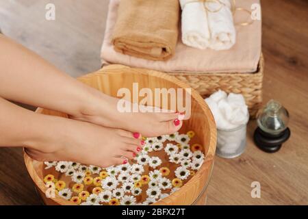 Femme mettant les pieds dans le bassin avec de la fleur perfusé eau chaude pour l'imprégner avant de faire la pédicure à la maison Banque D'Images