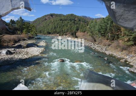 Des drapeaux de prière flottent sur un pont au-dessus de la rivière Bumthang, au Bhoutan. Banque D'Images