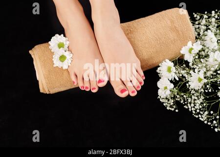 Femme reposant de beaux pieds soignés sur une serviette après avoir appliqué la lotion nourrissante Banque D'Images