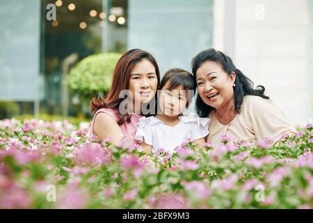 Portrait de trois générations de famille vietnamienne assis parmi des fleurs florales et regardant l'appareil photo Banque D'Images