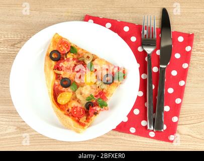 assiette avec une tranche de délicieuse pizza sur fond de bois Banque D'Images