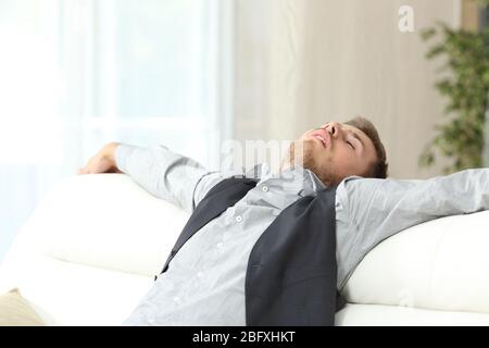 Homme d'affaires fatigué dormant après une journée de travail difficile assis sur un canapé à la maison Banque D'Images
