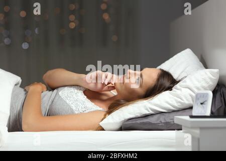 Pensive sérieuse femme pensant allongé sur le lit dans la nuit à la maison Banque D'Images