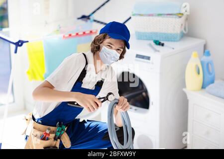 Service d'urgence de plombier pendant l'éclosion de coronavirus. Technicien en masque facial répare la rondelle cassée. Entretien de l'appareil domestique et domestique dans Banque D'Images