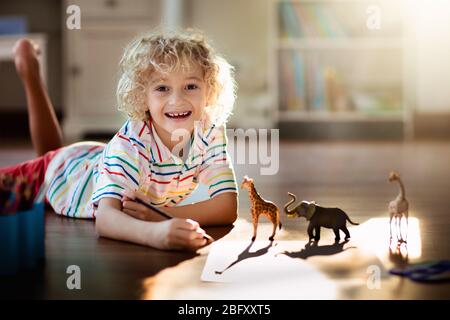 Enfants animaux de dessin d'ombre. Les enfants jouent à la maison. Artisanat amusant pour enfants de maternelle. Petit garçon peinture girafe et éléphant dans la chambre ensoleillée. Jeu Banque D'Images