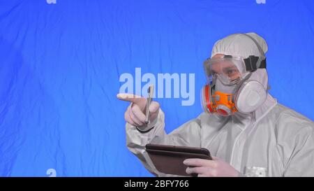 L'virologue scientifique dans le respirateur crée l'écriture dans un ordinateur tablette avec stylet. Homme portant un masque médical de protection. Touche Chroma bleu. Banque D'Images