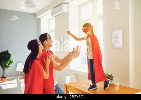 Famille heureuse de super héros jouant dans une salle à l'intérieur. Banque D'Images