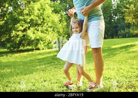 Fête des pères. Le père joue avec sa fille sur l'herbe dans le parc d'été une journée ensoleillée. Banque D'Images