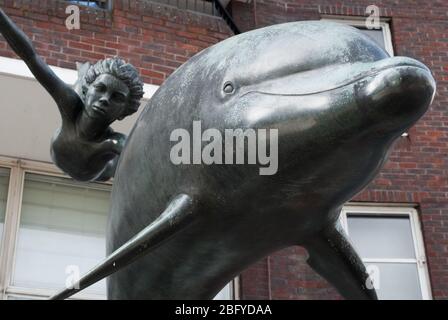 Garçon avec une statue de dauphin en bronze sur la promenade de Cheyne, Londres SW3 par Sir David Wynne Banque D'Images