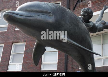 Garçon avec une statue de dauphin en bronze sur la promenade de Cheyne, Londres SW3 par Sir David Wynne Banque D'Images