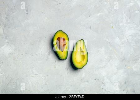 Avocat coupé en deux moitiés avec des graines sur fond blanc grunge. Banque D'Images