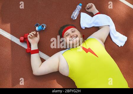 FAT paresseux dort fatigué se trouve sur la piste dans le stade. Banque D'Images