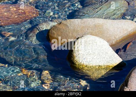 Ruisseau de montagne qui coule avec l'eau transparente et des pierres sur le bas. Banque D'Images