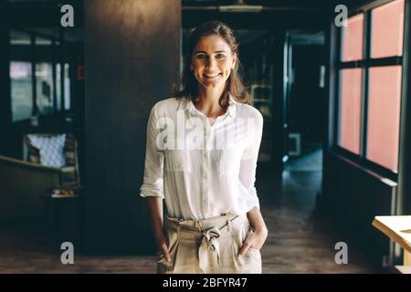Femme entrepreneur debout au bureau avec ses mains dans les poches. Femme d'affaires souriante debout au bureau. Banque D'Images