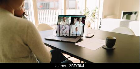 Réunion en ligne de l'équipe d'affaires par un appel vidéo sur ordinateur portable. Femme assise à la table à la maison ayant une conférence vidéo avec ses collègues. Banque D'Images