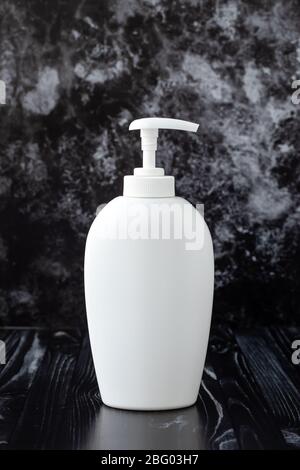 Bouteille distributeur en plastique blanc avec savon liquide sur fond en marbre noir dans la salle de bains. Concept d'hygiène personnelle Banque D'Images