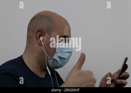 bald homme dans un masque passer un appel vidéo avec un casque Banque D'Images