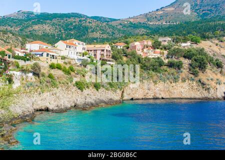 Vue sur une baie aux eaux turquoise et maisons traditionnelles colorées dans le village d'Assos, Kefalonia, Grèce Banque D'Images