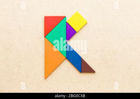 Puzzle en forme de lettre K en forme de tangram sur fond de bois Banque D'Images