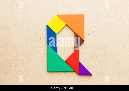 Puzzle en forme de lettre Q en forme de tangram sur fond de bois Banque D'Images