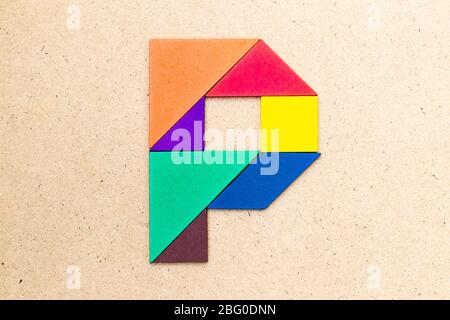 Puzzle en forme de lettre P en forme de tangram sur fond de bois Banque D'Images