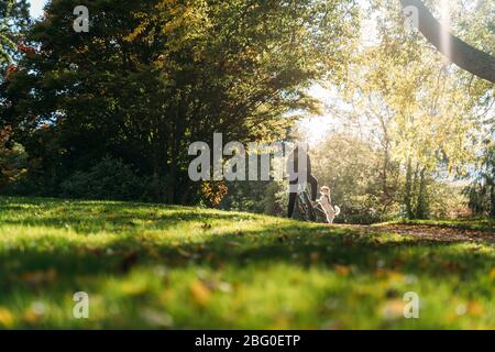 19/4/2020 femme asiatique avec un vélo alimentant un chien en automne dans le jardin botanique, Oamaru, Nouvelle-Zélande. Concept de l'exercice alors que l'isolement social fr Banque D'Images