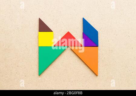 Puzzle en forme de lettre W en forme de tangram sur fond de bois Banque D'Images