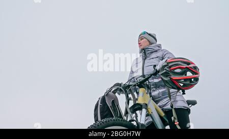 Femme se tient près de son vélo sur glace. La jeune cycliste s'est arrêtée à r Banque D'Images