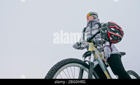 Femme se tient près de son vélo sur glace. La jeune cycliste s'est arrêtée à r Banque D'Images