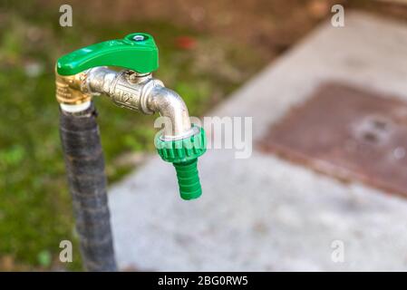 Gros plan sur un tuyau d'eau avec un robinet dans le jardin d'une maison au printemps Banque D'Images