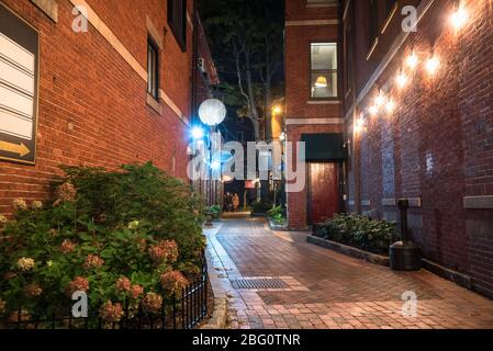 Ruelle étroite entre les bâtiments en briques anciennes avec des magasins et des restaurants au rez-de-chaussée la nuit Banque D'Images