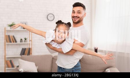 Petite fille et son père volant comme avion à la maison Banque D'Images