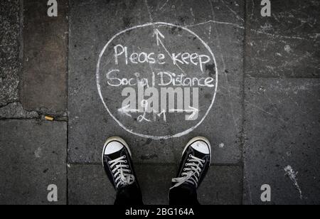 Dublin, Irlande - 19 avril 2020: Un message social distancing de deux mètres écrit dans la craie sur le pavé dans le centre-ville. Banque D'Images