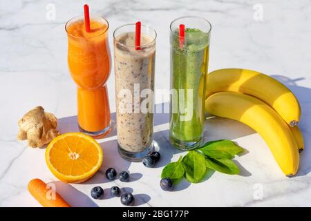3 différents types de smoothies avec des ingrédients sur table de marbre fond gigner banane bleuets épinards carotte . Banque D'Images