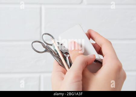Tenez les outils de manucure dans la main. Soin des ongles, procédure, salon de manucure. Brucelles, coupe-fils, poussoir, bâton orange pour arbres, ciseaux, lime à ongles. Pédicure, Banque D'Images