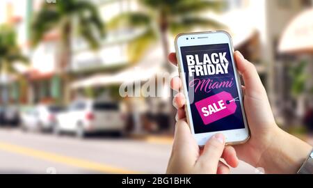 Vendredi noir Miami. Une fille à Miami tient un smartphone avec une publicité du vendredi noir à l'écran. Marketing, commerce électronique, publicité par téléphone cellulaire. Banque D'Images