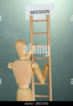 Mannequin sur échelle en bois, sur fond gris Banque D'Images