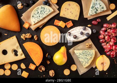 Fromage plat. Assortiment de nombreux fromages différents, dessus de la tête tourné sur un fond sombre Banque D'Images