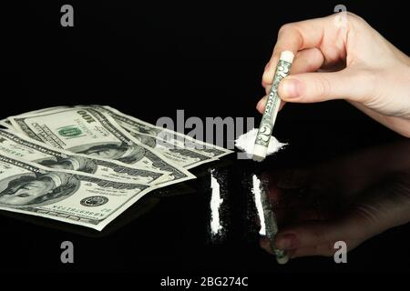 Les lignes de drogue de cocaïne et la tenue de main féminine ont enroulé le billet en dollars, gros plan Banque D'Images