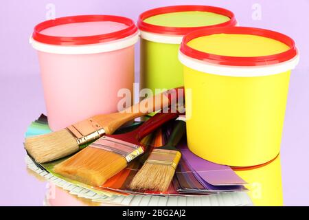 Set pour la peinture: Pots de peinture, pinceaux, palette de couleurs sur fond lilas Banque D'Images