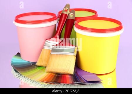 Set pour la peinture: Pots de peinture, pinceaux, palette de couleurs sur fond lilas Banque D'Images