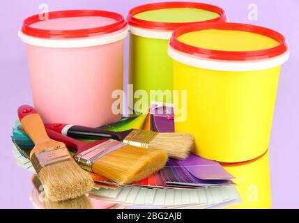 Set pour la peinture: Pots de peinture, pinceaux, palette de couleurs sur fond lilas Banque D'Images