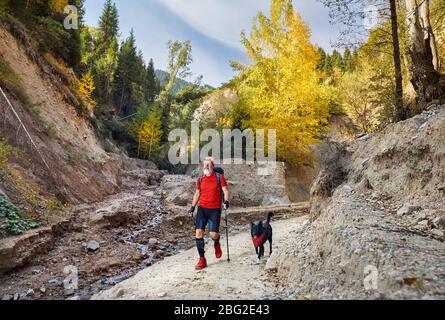 Vieil homme à barbe blanche et black dog walking dans canyon au temps d'automne. Outdoor travel concept Banque D'Images