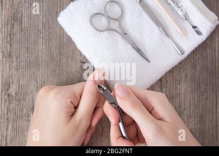 Une femme fait une manucure à la maison. Outils de manucure. Manucure à bordure. Couper, plaie sur le doigt, sang. Manucure dangereuse. Soins à domicile, spa, beauté. SAL des ongles Banque D'Images